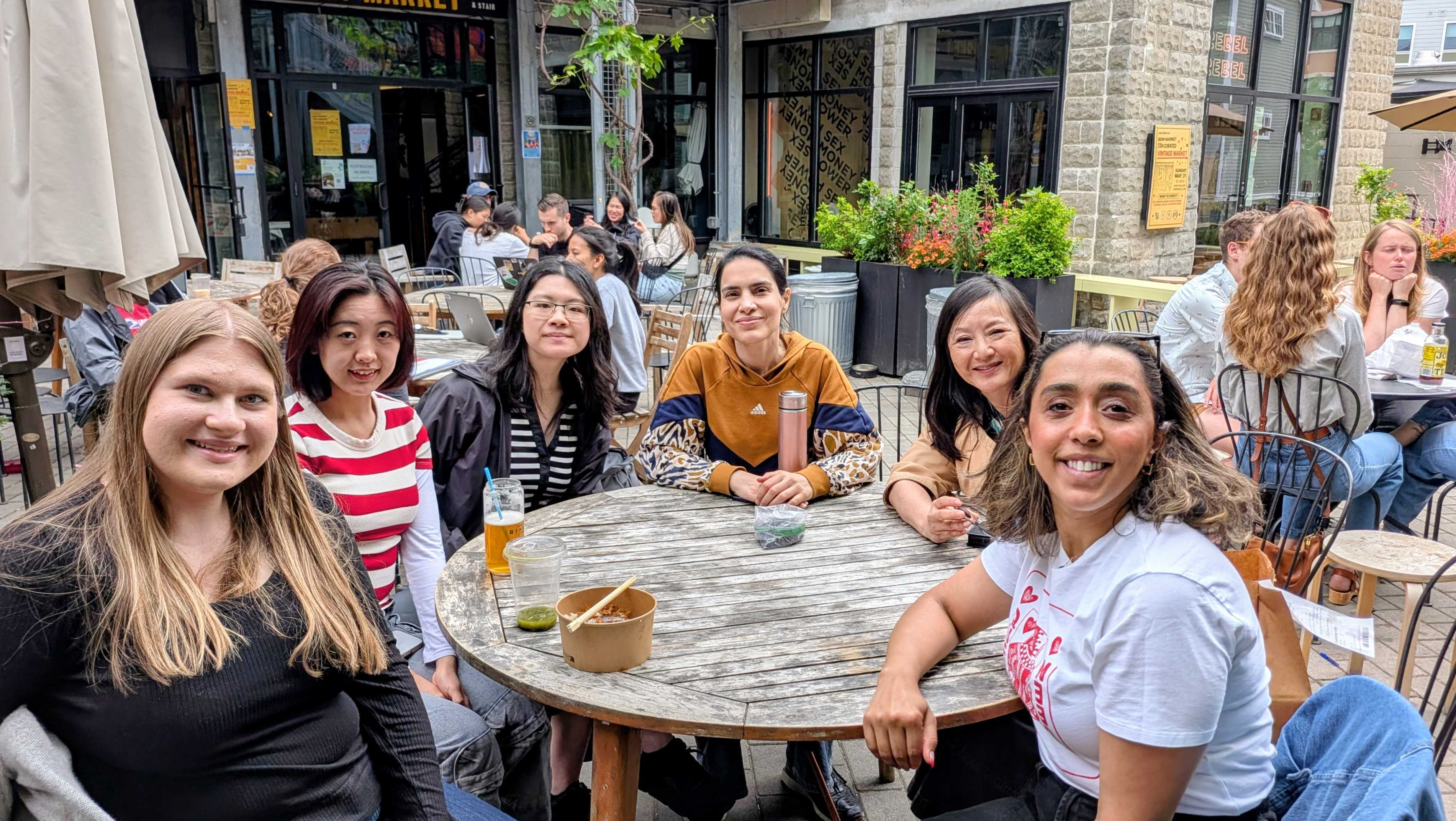 Boston Women in Bioinformatics members smiling seated along a round wooden table.