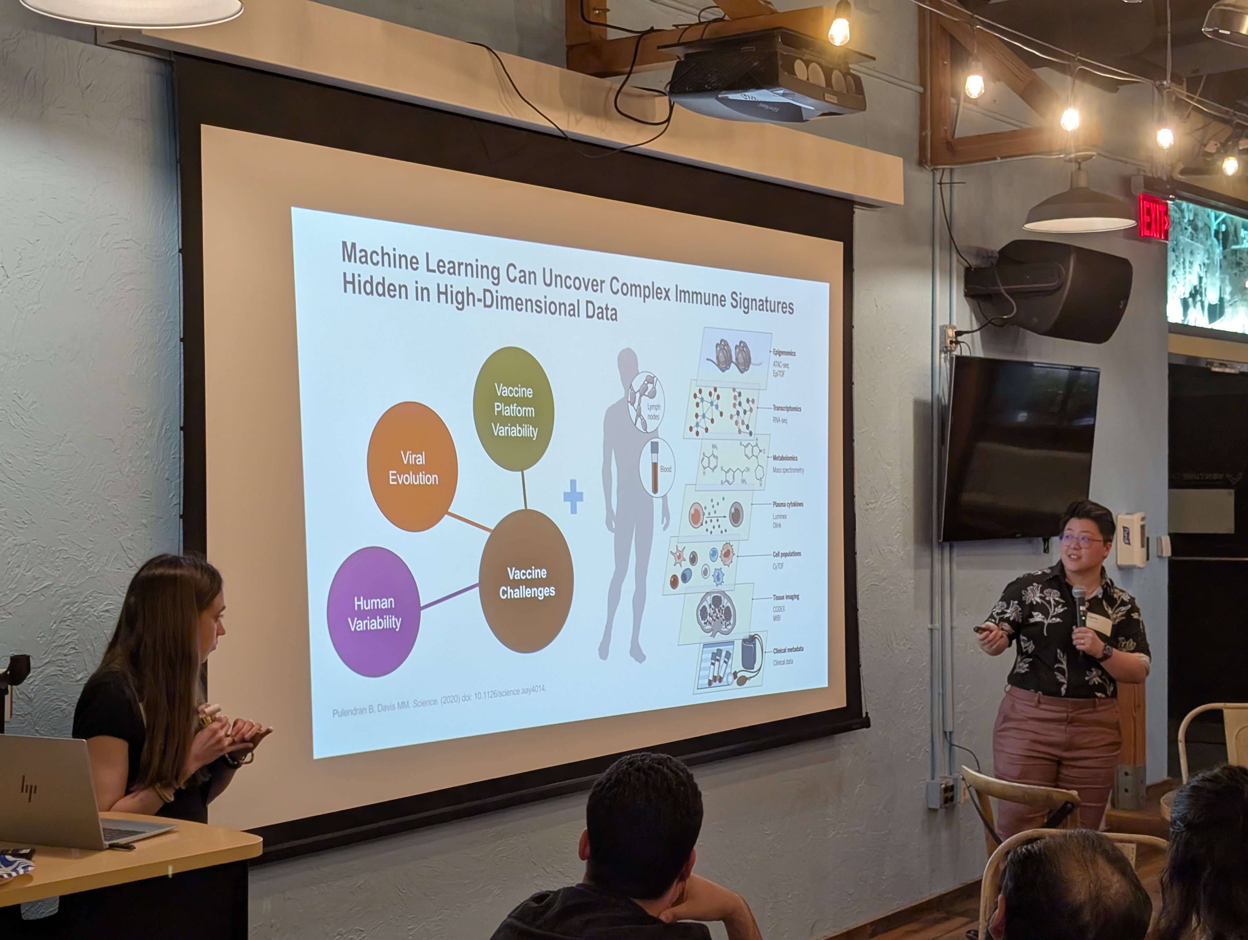 Stephanie Hao presents a slide captioned "Machine Learning Can Uncover Complex Immune Signatures Hidden in High-Dimensional Data" with a network illustrating the various challenges and dimensions of the biological data